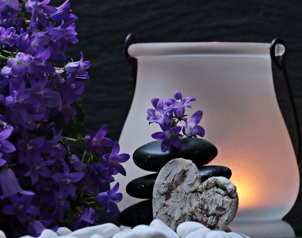 stacked river rocks with purple flowers and candle